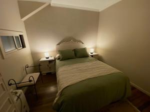 1 dormitorio con 1 cama con sábanas verdes y 2 lámparas en O pisiño de Isa, en Noia