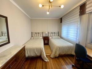 Un dormitorio con dos camas y un escritorio y una ventana. en O pisiño de Isa, en Noia 2 fotos más