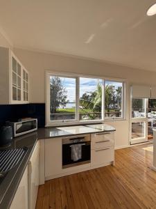 a kitchen with white cabinets and windows and a wooden floor at Sunrise on the Water in Lemon Tree Passage +8 photos