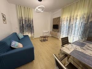 a living room with a blue couch and a table at Luris apartament Himare in Himare
