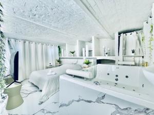 a white bedroom with a tub and a bed at 9 Mykonos , Spa Balnéothérapie - espace aménagé privatif avec Lit Double in Tourcoing