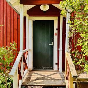 a green door on a red house with a porch at Visthuset, historical cottage at Långnäs Manor in Långnäs