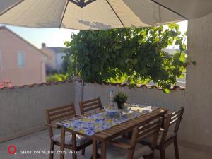 a table with chairs and an umbrella on a patio at Apartman Lunna in Vrsi