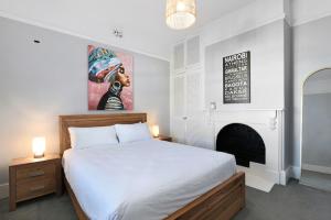 ein Schlafzimmer mit einem weißen Bett und einem Kamin in der Unterkunft Charming 2-Bed House in North Hobart in West Hobart