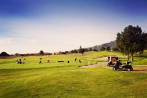 a golf cart parked in a field with people playing at Apartment Bonmont in Bonmont Terres Noves