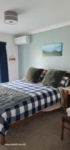 a bed with a blue and white checkered blanket at Tui Glade Bed and Breakfast in Cambridge