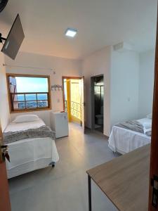 a room with two beds and a table in it at Pousada Recanto das Estrelas in São Thomé das Letras