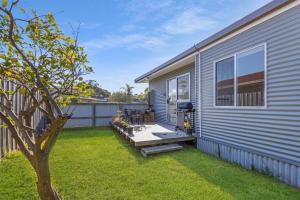 un patio trasero con terraza y una casa en Seaside Escape, en Lakes Entrance
