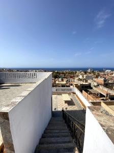 een trap naar een gebouw met de oceaan op de achtergrond bij Adem s6 in 'Aïn el Turk