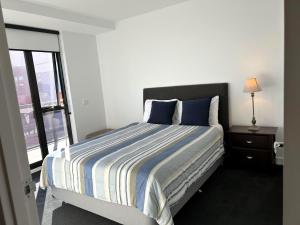a bedroom with a bed with blue pillows and a window at PROMENADE TOWERS 2 Bedroom Apartment with City Views on the Geelong Waterfront - 506 in Geelong
