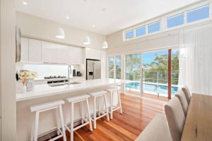 a kitchen with white cabinets and a counter with stools at The Lookout in Corlette