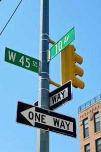 a pole with two one way signs and a traffic light at Studio apart Time Square in New York