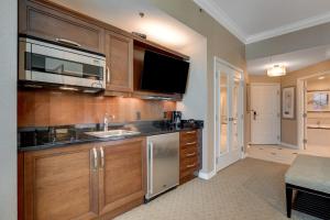 una cucina con armadi in legno, lavandino e TV di Solstice Studio at MGM Signature Tower 3 BALCONY STRIP VIEW F1 TRACK VIEW a Las Vegas