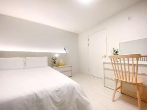 a white bedroom with a bed and a wooden chair at Luxury for family, terrace, 3room,2bath,metro 1min in Seoul