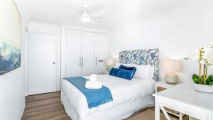 ein weißes Schlafzimmer mit einem blauen und weißen Bett in der Unterkunft Beachpoint 402 in Forster