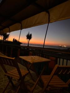 a table and chairs on the beach at sunset at Hostal El Ancla in Caldera