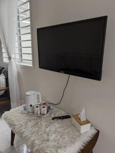 a living room with a table with a television on a wall at Homestay Apamanis, Alor Setar in Kepala Batas