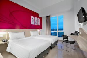 Una habitación de hotel con dos camas y una pared roja. en favehotel Tuban, en Tuban