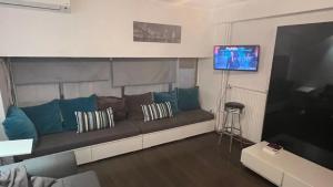 a living room with a couch and a flat screen tv at Loft for 4 to the center of Thessaloniki in Thessaloniki