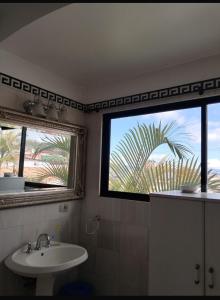 a bathroom with a sink and a window with a palm tree at Modern Mediterranean Santorini House in Cartago