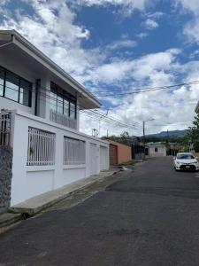 a white house with a car parked on the street at Modern Mediterranean Santorini House in Cartago