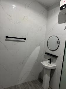 a white bathroom with a sink and a mirror at Sohana Homes in Ikeja