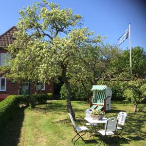 a table and chairs in a yard with a flag at Haus am Deich in Utersum