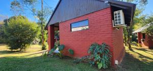 a red house with a black roof and a window at El Pueblito Lodge in El Soberbio