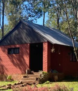 una casa de ladrillo rojo con techo negro en El Pueblito Lodge, en El Soberbio