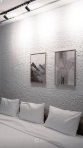 a bed with three pictures on a white wall at Taradol Premium by Tukta in Hua Hin +30 photos