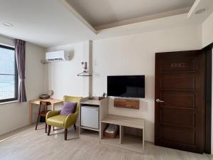 Cette chambre dispose d'une télévision et d'un bureau avec une chaise. dans l'établissement 日安蝸牛, à Tainan