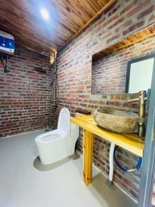 a bathroom with a brick wall and a sink and a toilet at lúa Cafe Eco Lodge in Sapa