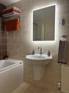 a bathroom with a sink and a mirror and a tub at Prime Port Apartment in Portstewart +14 photos