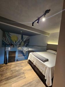 a bedroom with a bed and a painting on the wall at Lofts 4 Elementos - Ar - Martim de Sá - Caraguatatuba in Caraguatatuba