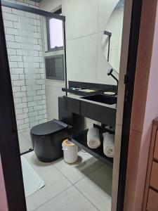 a bathroom with a black toilet and a mirror at Lofts 4 Elementos - Ar - Martim de Sá - Caraguatatuba in Caraguatatuba +15 photos