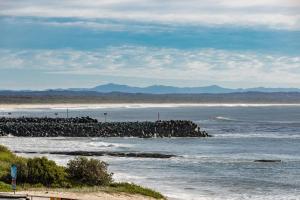 una playa con un montón de rocas en el agua en Ebbtide 8, en Forster