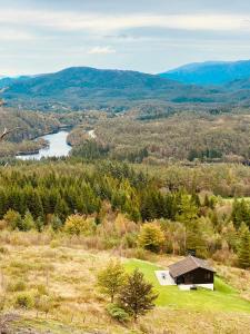 een huis op een heuvel met uitzicht op een rivier bij Panoramic Cabin With Forest And Mountain Views in Sveio +17 foto's