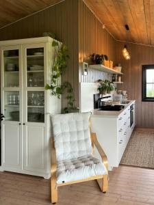 een keuken met witte kasten en een witte stoel bij Panoramic Cabin With Forest And Mountain Views in Sveio