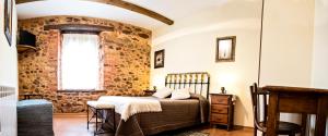 1 dormitorio con cama y pared de piedra en Hotel Rural El Habanero, en Destriana