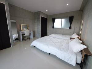 Un dormitorio con una gran cama blanca y un escritorio. en RICCA Miyako, en Isla Miyako