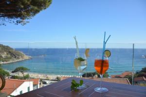 two glasses on a table with a view of the ocean at Hotel Baia Imperiale in Campo nell'Elba