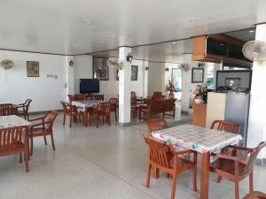 a dining room with tables and chairs and a television at SA hotel in Trat