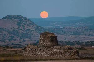 a full moon rising over a stone building with a stone wall at Agriturismo Le Mimose in Arborea