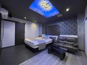 una camera da letto con un letto, un divano e una TV di ホテルアテネ 市原鶴舞インター店 a Ichihara
