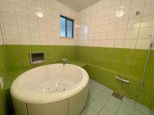 un bagno verde e bianco con vasca e finestra di ホテルアテネ 市原鶴舞インター店 a Ichihara