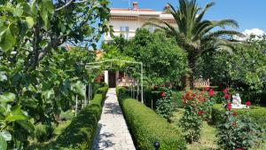 un giardino con una casa e alcuni cespugli e alberi di Guesthouse Mira a Rab