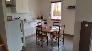 cocina con mesa, sillas y nevera en L'appartement Du Bien être, en Damblain