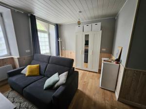 a living room with a blue couch with yellow pillows at Studio proche centre-ville Dol-de-Bretagne in Dol-de-Bretagne