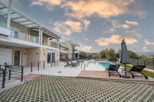 a villa with a swimming pool with chairs and an umbrella at Rastoni Luxury Home in Pogoniá
