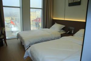 due letti in una camera d'albergo con finestra di 合悦精品商务酒店 a Roga